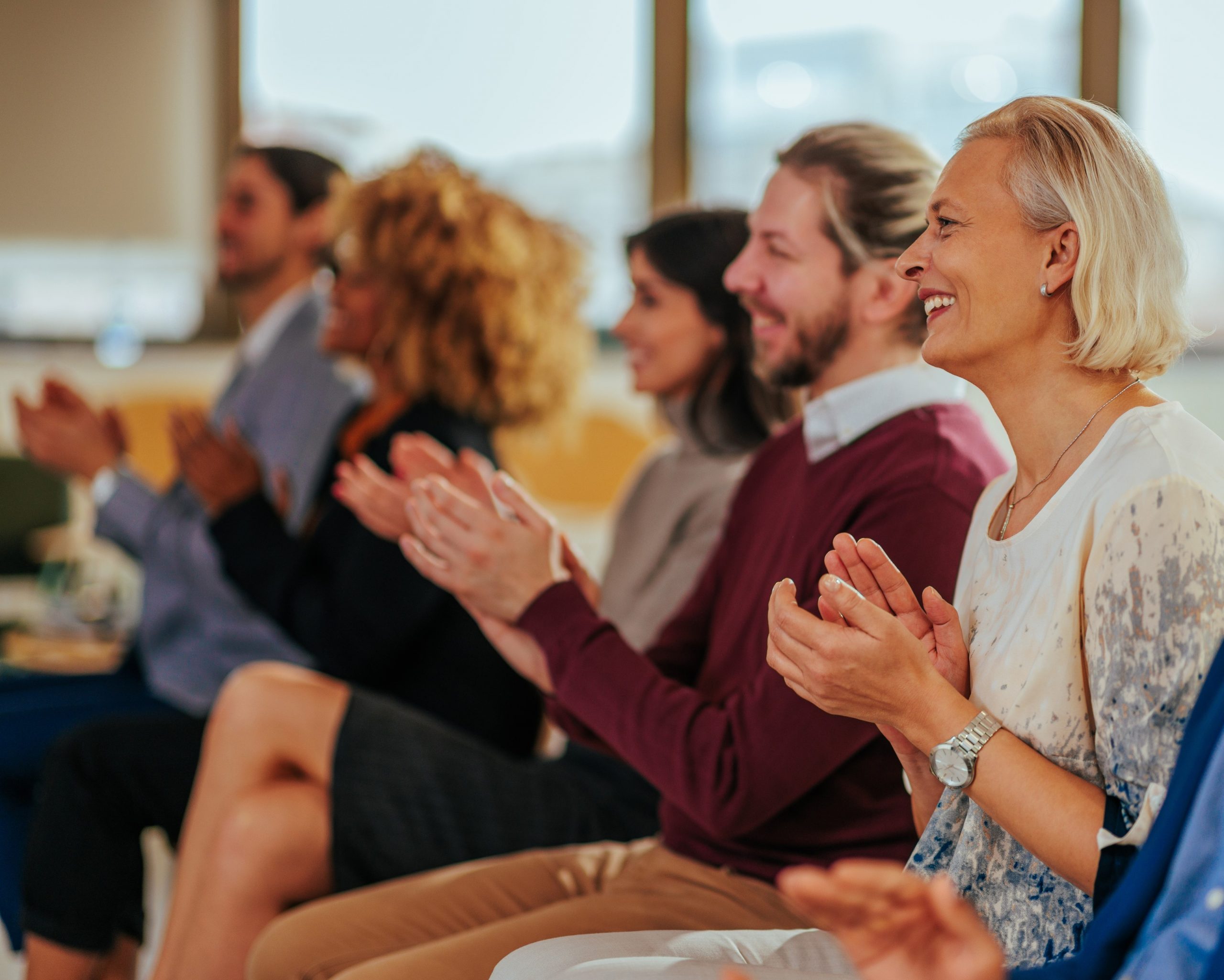 people at seminar smiling and clapping hands